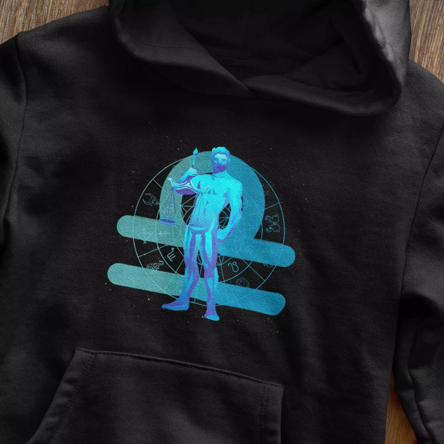 Black hoodie featuring artistic Libra scales balance design, ideal for astrology enthusiasts – Μαύρο φούτερ με κουκούλα που παρουσιάζει καλλιτεχνικό σχέδιο ισορροπίας ζυγαριάς Ζυγού, ιδανικό για λάτρεις της αστρολογίας.