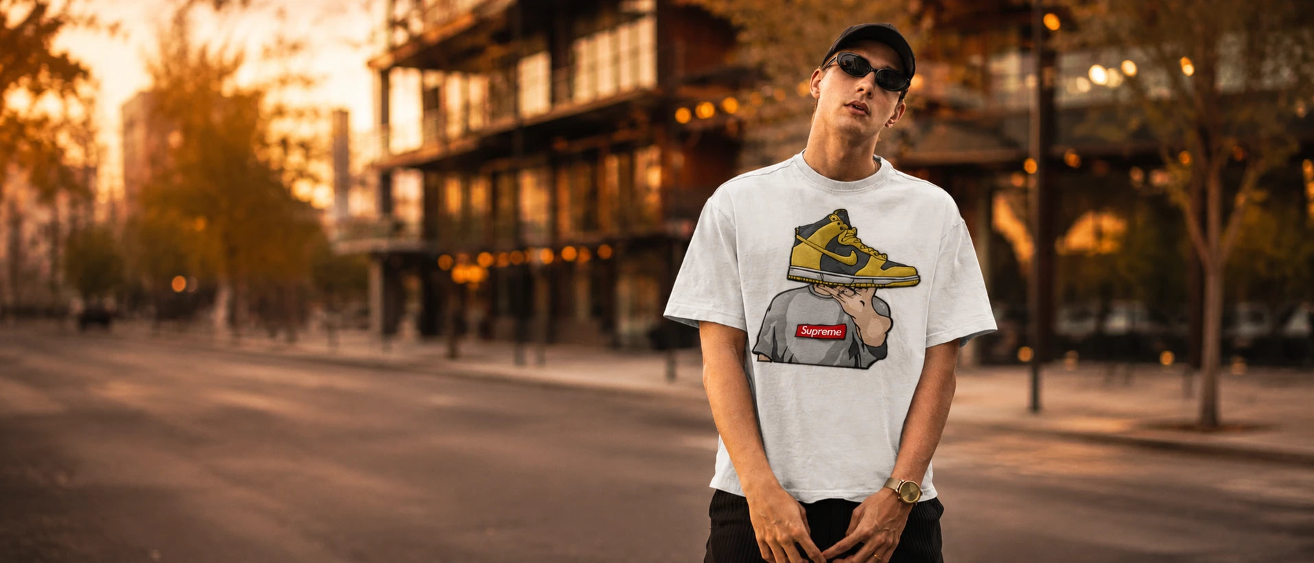 Premium streetwear fashion banner featuring a model wearing a white oversized embroidered sneaker graphic t-shirt with cinematic city background - Streetwear banner με μοντέλο που φορά λευκό oversized tshirt με κέντημα