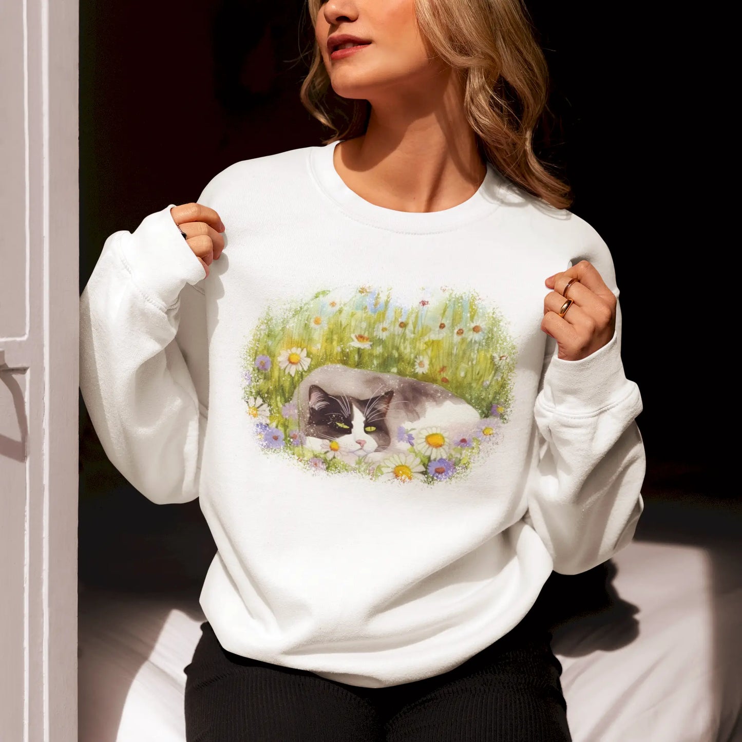 Soft white sweatshirt featuring dreamy cat artwork nestled between blooming daisies and grass - Απαλό λευκό φούτερ με ονειρικό έργο τέχνης γάτας φωλιασμένο ανάμεσα σε ανθισμένες μαργαρίτες