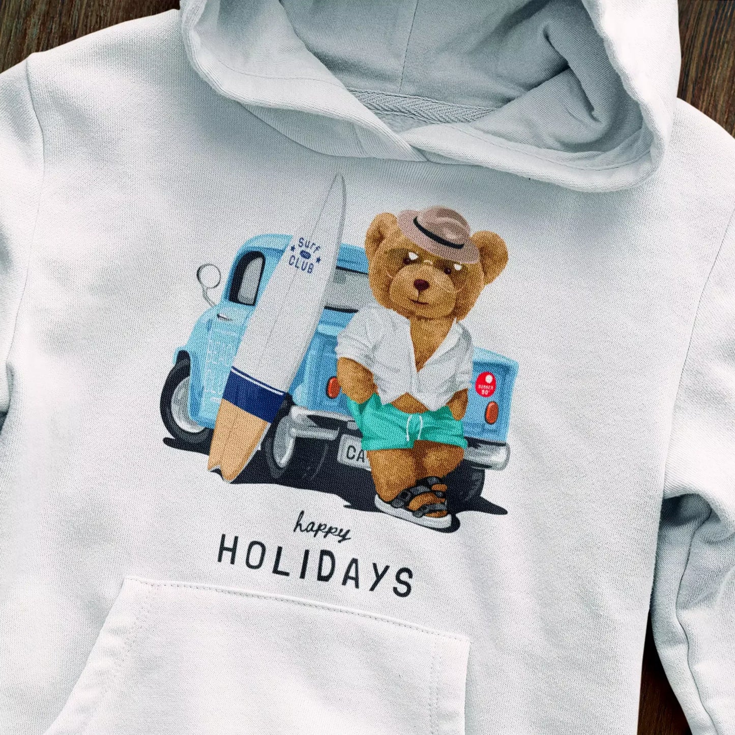 Summer-ready teddy in beach look on white hoodie – Αρκουδάκι με καλοκαιρινό beach look σε λευκό hoodie.
