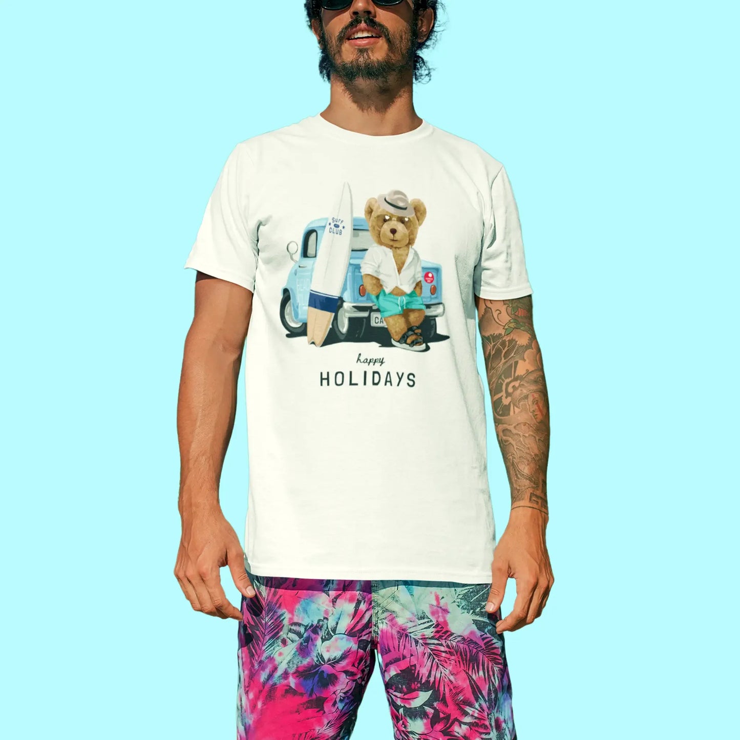 Teddy holding surfboard in front of van printed on white shirt – Αρκουδάκι με σανίδα του surf μπροστά σε βαν σε άσπρη κοντομάνικη μπλούζα.