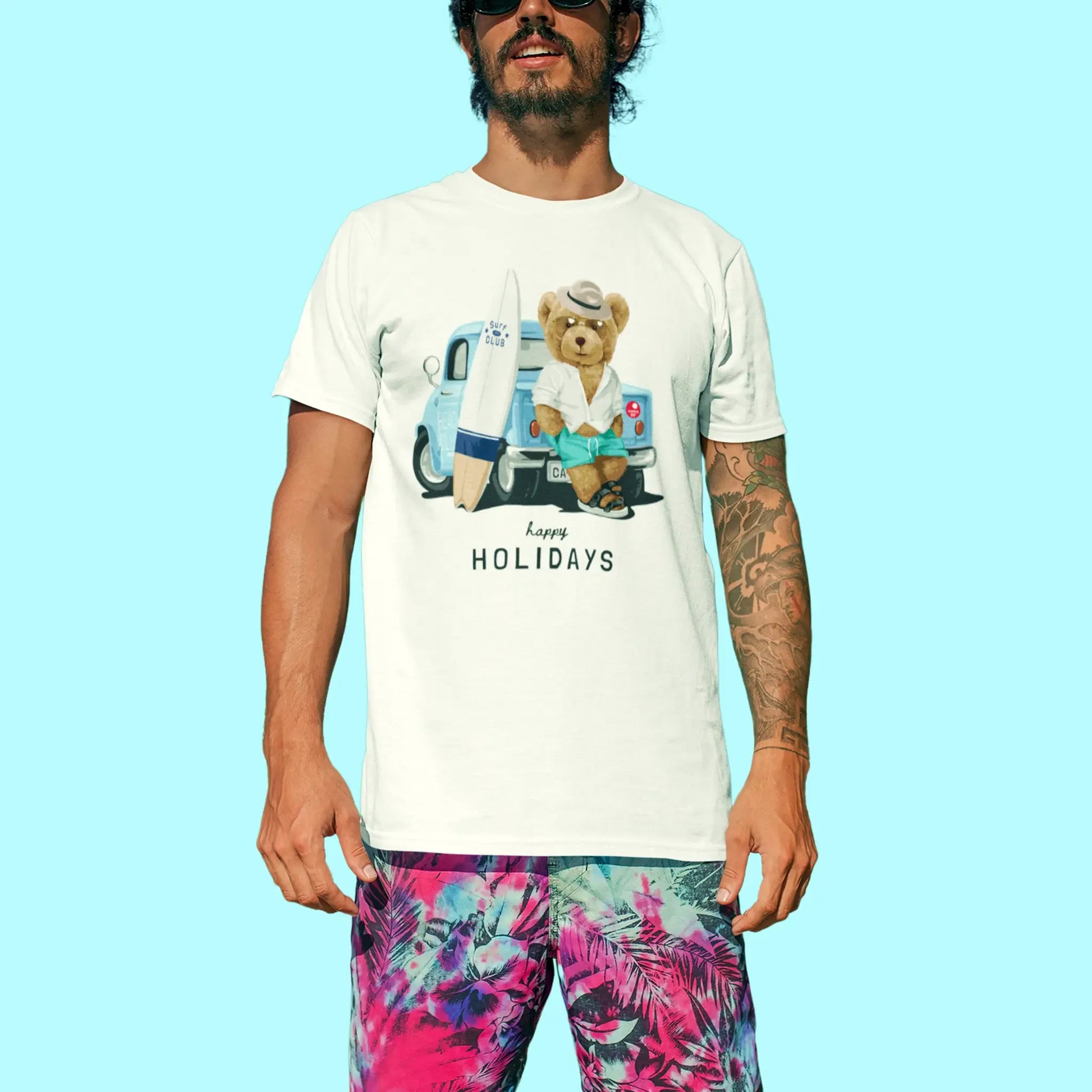 Teddy holding surfboard in front of van printed on white shirt – Αρκουδάκι με σανίδα του surf μπροστά σε βαν σε άσπρη κοντομάνικη μπλούζα.