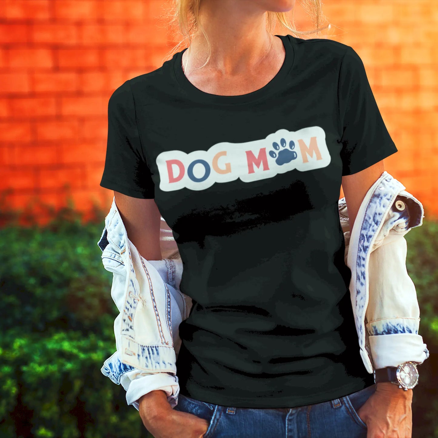 The black tee pops with the soft pastel “Dog Mom” lettering and bold paw icon, a must-have for stylish pet moms – Το μαύρο μπλουζάκι τονίζει τα απαλά παστέλ γράμματα του “Dog Mom” και τη δυναμική πατούσα, απαραίτητο για κάθε κομψή μαμά σκύλου.