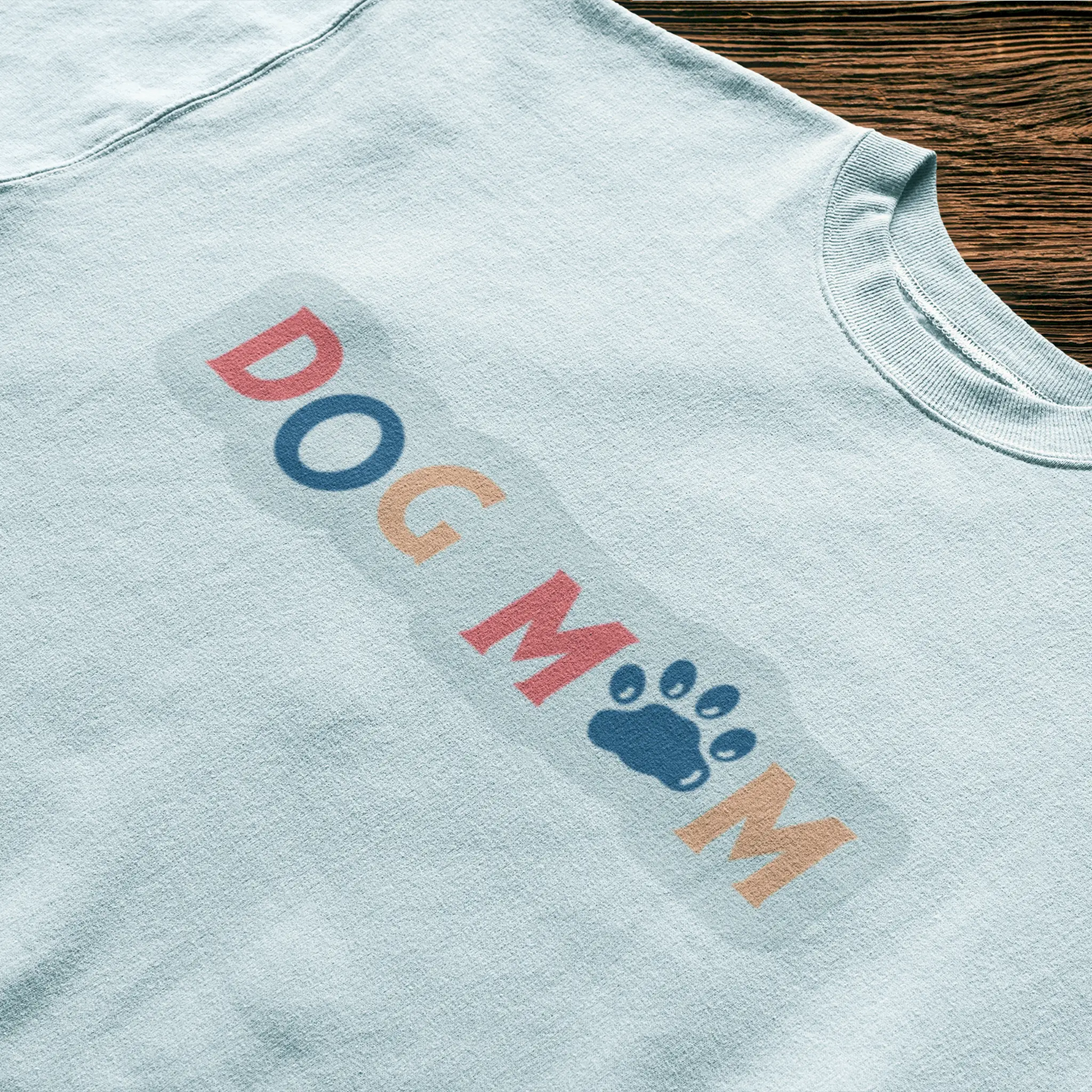 This white shirt turns heads with its joyful “Dog Mom” design that blends fun fonts and soft tones – Αυτό το λευκό μπλουζάκι τραβάει τα βλέμματα με το χαρούμενο design “Dog Mom” που συνδυάζει παιχνιδιάρικα γράμματα και απαλούς τόνους.