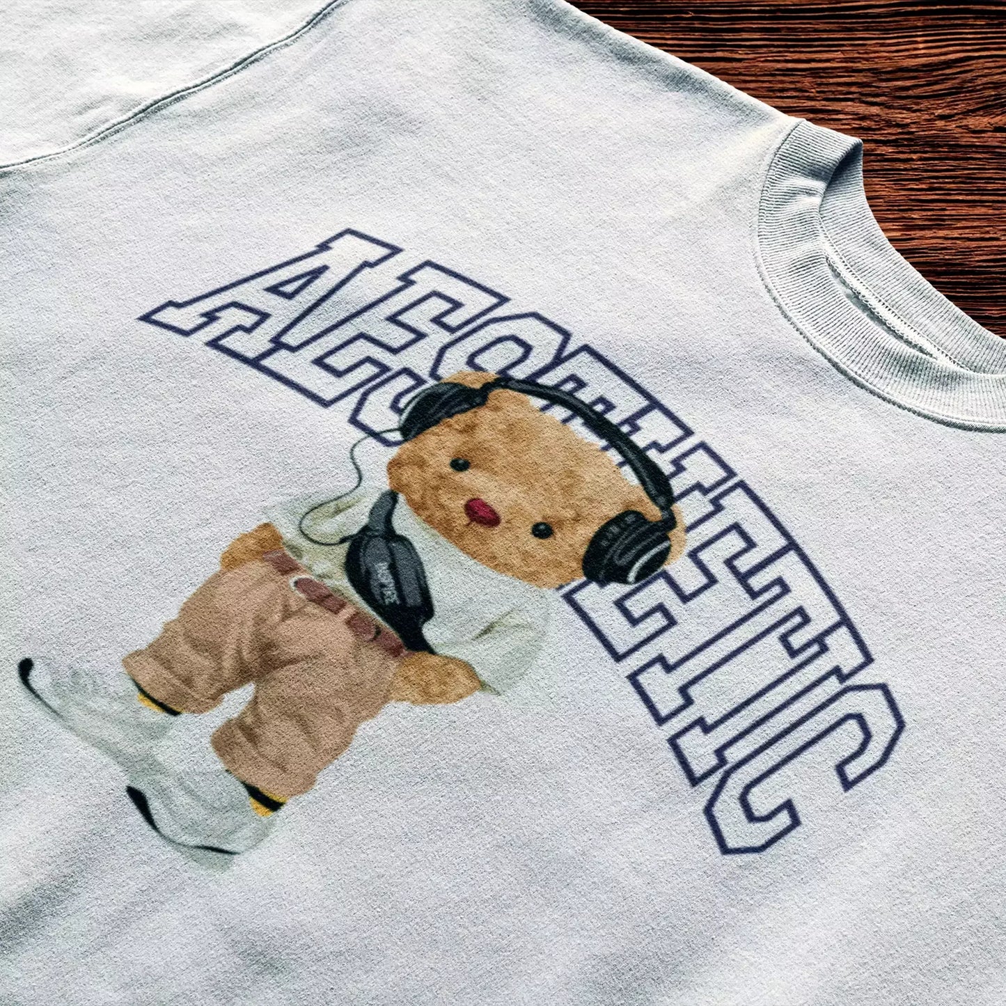 White t-shirt featuring teddy in neutral outfit and headphones – Λευκό t-shirt με teddy σε ήρεμο look και ακουστικά.