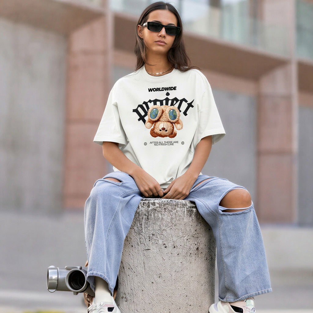 Woman model wearing a white oversized streetwear t-shirt with premium embroidered teddy bear graphic - Γυναίκα μοντέλο με λευκό oversized streetwear t-shirt και κεντημένο αρκουδάκι Worldwide Project