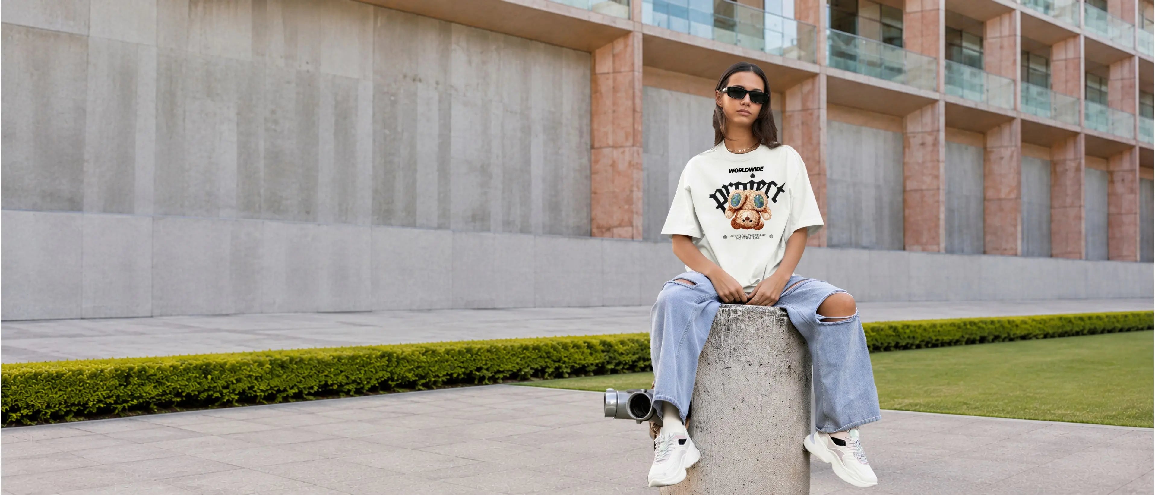Woman wearing a white oversized streetwear t-shirt with premium embroidered teddy bear graphic in an urban setting - Γυναίκα μοντέλο με λευκό oversized streetwear t-shirt και ανάγλυφο κεντημένο σχέδιο